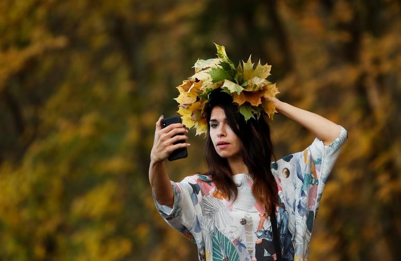 A woman takes a selfie with yellow leaves in a park in Moscow, Russia October 14, 2020. REUTERS/Maxim Shemetov